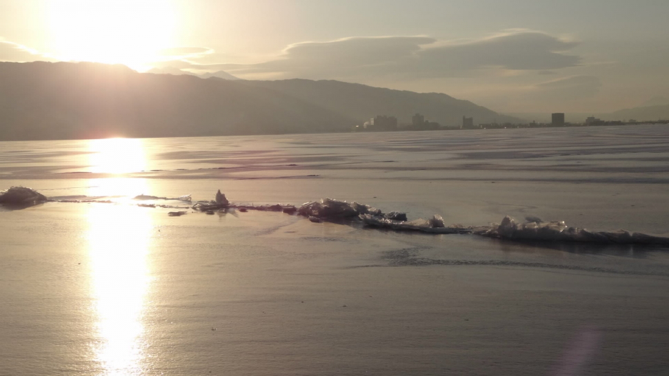 日の出に全面結氷の湖面が輝く